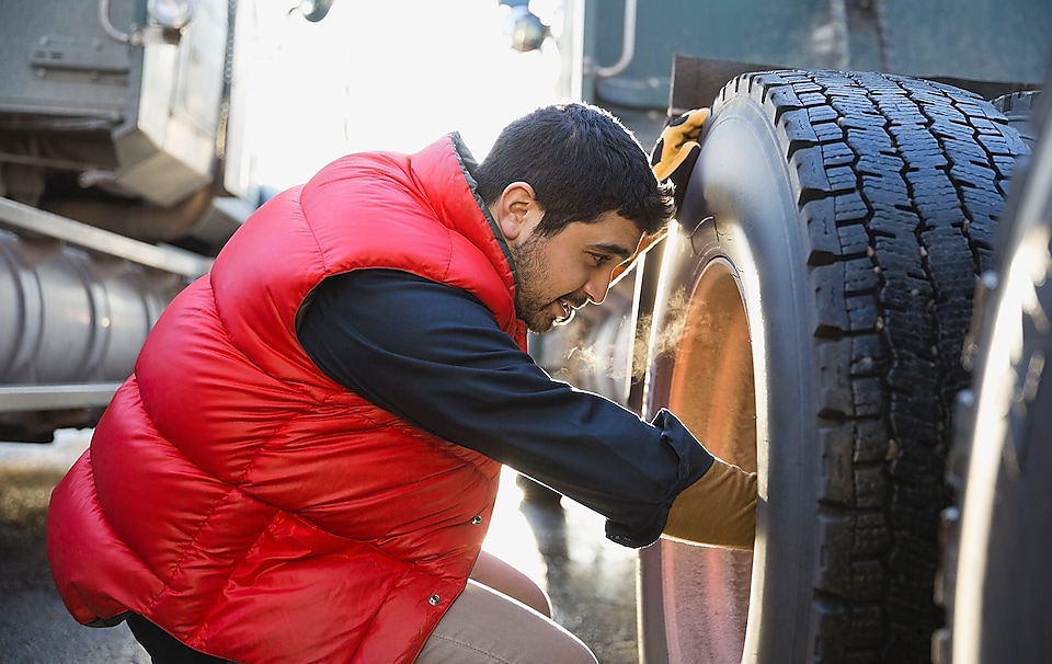 Worker checking truck tyre