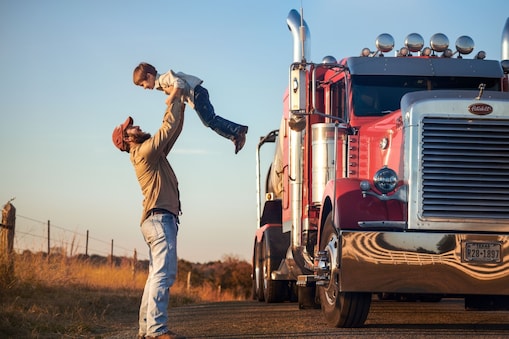 man happily playing with son near red truck