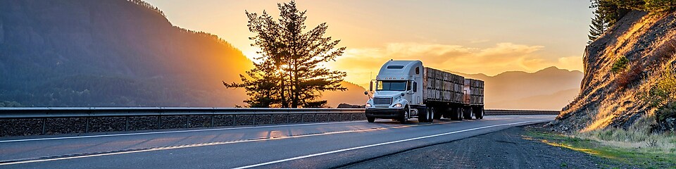 camion semi-remorque sur l’autoroute et soleil couchant en arrière-plan